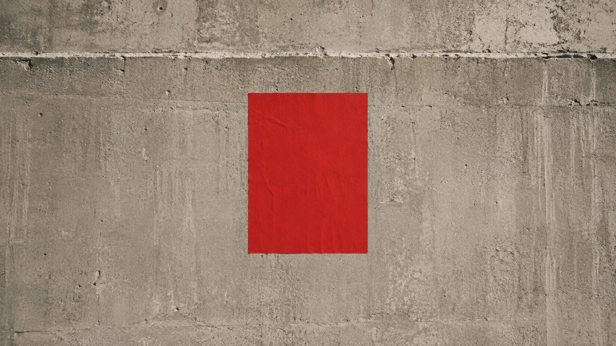 Cartel rojo pegado en un muro liso, metáfora de una marca que se recuerda